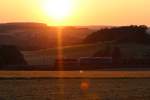 Holzvollzug mit ziehender 112 565 und 155 045 der Press bei Sonnenuntergang schlängeln sich durch das Vogtland nach Plauen. Gesehen am 30.6.2015