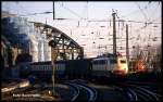 114491 verlässt mit einer bunten Wagengarnitur die Hohenzollern Brücke in Köln und erreicht somit in der letzten Abendsonne am 30.11.1989 den Kölner HBF.