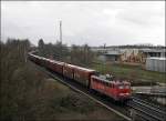 140 572-9 fhrt mit einem Autoteilezug an einem Baumaschinenhndler vorrber.