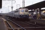 141151 an 5.7.1988 um 18.38 Uhr vor einem Nahverkehrszug nach Frankfurt am Main im Bahnhof Hanau.