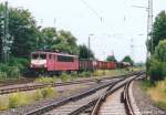 155 133 erreichte am 30.6.04 mit einem Güterzug nach Nürnberg den Bahnhof Hallstadt. Mitten im Weichenbereich lag damals noch ein beschrankter Bahnübergang, und der Fotograf stand hinter dem herunter gelassenen Schrankenbaum. 