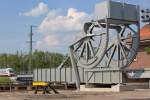 Die restaurierte (ehemalige) Eisenbahn-Rollklappbrücke in Anklam wurde als technisches Denkmal über die Peene aufgestellt und ein ICE verlässt in diesem Augenblick die neue