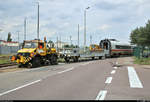 Ein Mercedes-Benz Unimog (Zweiwegefahrzeug) rangiert mit einem Flachwagen und dem Endwagen 411 052-4 von Tz 1152  Travemünde  in der Eisenbahnstraße auf dem Gelände der Maschinenbau und