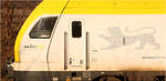 Ein Fake-Seitenfenster mit Rückspiegel - ein teilweiser Lokführer-Schattenriss - und ein Go-Ahead BW-Löwe -     Mitzieher eines fünfteiligen Flirt-3-Triebwagen der als MEX 13