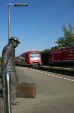 Warten auf den Zug - doch in diesen einfahrenden RB nach Lindau wird die ewig wartende Skulptur in Nonnenhorn sicher nicht einsteigen.
