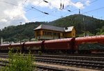 Eine fast unendlich scheinende Reihe von Tragwagen mit Plane stehen vor dem alten Reiterstellwerk des Bahnhof Finnentrop,2.7.2016