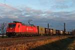 Am Morgen des 23.12.2017 fuhr BRLL/XRAIL 185 595-6  Ruth  mit einem Containerzug bei Hügelheim durch die frisch aufgegangene Sonnen in Richtung Schweizer Grenze.