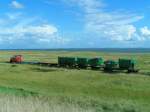 Ein Mllzug wird durch die Salzwiesen zum Hafen geschoben;   Die beladenen Container werden dann mittels Gabelstapler auf die Fhre umgeladen und ins Festland zur Entsorgung transportiert.
