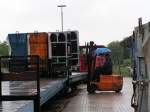 Bei strmenden Regen entldt der Bahnhofvorstand die Rollcontainer mit dem Gepck der Touristen.