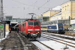 DB 111 087 mit RE 2 (4859) Hof - München in Regensburg, 20.02.2026. Im Hintergrund ein wegen vereister Wagen  verendeter  ALEX.