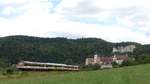 Der Hzl  Naturpark-Express  Sigmaringen - Blumberg-Zollhaus verlässt Beuron mit dessen Kloster und einigen Bergen im Hintergrund.