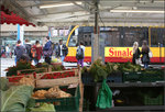 Erdbeeren und Stadtbahn -    Blick über einen Marktstand zur gerade abfahrenden Stadtbahn.