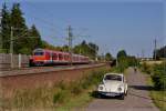 Ein Zug der Linie S2 der Nürnberger S-Bahn wird von einer Lokomotive der Baureihe 143 von Roth in Richtung Nürnberg Hbf geschoben, während es sich mein VW Käfer am Wegesrand