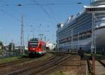 Ein FLIRT-Triebwagen machte sich am 27.07.2008 als S1 von Rostock-Warnemnde  auf nach Rostock Hbf  und passierte kurz hinter seinem Startbahnhof das Kreuzfahrtschiff  Crown Princess .