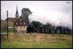 Hammerunterwiesenthal am 8.10.1992: Um 11.02 Uhr kommt 99740 mit dem Personenzug nach Oberwiesenthal an dem bekannten Fotopunkt mit Kirchturm im Hintergrund daher.