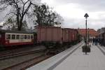 Der Foto-Gterzug der HSB, aufgenommen am Mittag des 18.10.2013 auf Gleis 32 im HSB-Bahnhof Wernigerode. Wie an den Schmierutensilien in Hhe des zweiten Wagens zu erkennen ist, wird er auf seinen bevorstehenden Einsatz als rollende Fotokulisse fr einen Sonderzug der IG HSB, welcher am nchsten Tag erfolgen soll, vorbereitet. Auf dem Bahnsteig versammeln sich langsam bereits die Fahrgste fr den heutigen Sonderzug des genannten Vereins, der in wenigen Minuten, unter Traktion von 99 5901, zum Brocken startet.