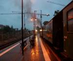 Blick vom Schmalspurbahnsteig in Radebeul Ost auf den abfahrbereiten Lnitzdackel und die Baustelle im nrdlichen  Bahnhofsbschnitt bei strmendem Regen.