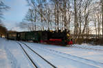 Der RASENDE ROLAND mit der Lok 994632 fährt an den verschneiten Bahnsteig des Bahnhofs Binz LB.