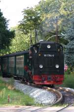 Am 19.08.2010 zieht 99 1784 - 0 den vorletzten Zug  von Binz nach Ghren gegen 18:36 Uhr , die Bahn kreuzt hier in Baabe die Strandstrae, eine schne Promenade, die geradewegs zum Ostseestrand fhrt.