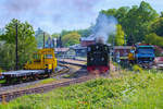 Zwischen abgestellten Fahrzeugen fährt der Rasende Roland in Putbus aus dem Bahnhof. - 25.05.2017