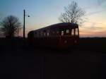 Triebwagen T102 wird vom Abendlichen Osterfeuer vor der Wagenhalle angestrahlt.