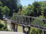 Die Bergbahn Künzelsau -    Knapp am Rand entlang ist diese talwärts fahrende Bahn auf der aufgeständerten Strecke kurz vor der Fachwerkbrücke an deren unterem Ende sich die