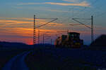 Eine Stopfmaschine und eine Schotterplaniermaschine im Abendlicht bei Oberdachstetten Richtung W�rzburg, 28.03.2022