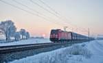 Die 185 244-1 fährt bei Sonnenaufgang in Langenisarhofen mit einem Kokszug vorüber.Bild vom 20.1.2017