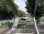 Die Dortmunder U47 im Westfalendamm -     Blick zwischen zwei der Stahlbögen der Dachkonstruktion der Station Hauptfriedhof auf die Strecke mit einem einfahrenden B80C-Stadtbahnwagen.