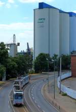 An den Silos der Ölmühle Sels im Neusser Hafen vorbei fährt ein Rheinbahnzug der Linie U 75 am 11.06.2015 in die Station Neuss Am Kaiser ein