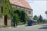Durch Freiburg-Haslach ins Rieselfeld -    Eine GT8Z-Straßenbahn fährt an der Kirche Sankt-Michael in die Ortsdurchfahrt von Haslach ein und wird gleich die Haltestelle 'Scherrenplatz'