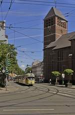 An der Bilker Kirche wird der GT6 2501 mit dem Bw 1689 auf seinem Weg vom Düsseldorfer Hauptbahnhof nach Hamm gleich nach links in die Gladbacher Straße abbiegen (09.06.2019). Dieser Triebwagen wurde 1956 gebaut und ist der weltweit erste der sehr erfolgreichen DUEWAG-Gelenkwagen. Er wurde in den Ablieferungszustand mit grauen Zierstreifen (bis weit in die 1970er Jahren gab es rote Zierstreifen nur bei den Fernbahnen) und Schaffnerplatz zurückversetzt.