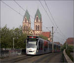 Über den Hauptbahnhof hinweg in den Freiburger Westen -    Eine Combino-Tram fährt die westliche Rampe zur Stühlinger Brücke hoch und wird gleich die Haltestelle Hauptbahnhof