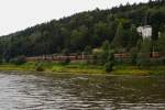 Ein Kohle-Zug in Richtung Tschechien ist am 30.08.2012 unterwegs im Elbtal, hier in Hhe der Stadt Bad Schandau. Auch wenn es es vom Licht her so aussieht, es ist nicht Abend, sondern erst Nachmittag. Die Dunkelheit stammt von einer gewaltigen Gewitterzelle, welche sich soeben ber das Elbtal schiebt! (Aufnahme vom Personendampfer  Meissen  aus)