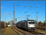 187 313-2 der HSL fährt am 01.03.2026 mit einem Autozug durch den Bahnhof Biederitz. Links ist das markante, 1983 errichtete Stellwerksgebäude zu sehen, das ein GS II-Stellwerk beherbergt. 