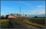 186 383 der HSL kreuzt auf dem Weg Richtung Magdeburg mit einem BLG-Autozug die wenig befahrene Straße von Güterglück nach Töppel.