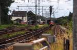 ber den geschlossenen Schrankenbaum hinweg eine Teleaufnahme auf den Bahnhof Grevenbroich.