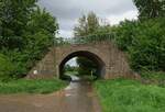Seit mehr als 100 Jahren durchschneidet ein 13 km langer Bahndamm, auf dem nie ein Zug fuhr, die niederrheinische Landschaft zwischen Neuss-Holzheim und Rommerskirchen. Ursprünglich war lediglich eine eingleisige Strecke zur Abfuhr von Braunkohle aus dem Bergheimer Raum zum Rheinhafen Neuss geplant, doch 1912 wurde das Vorhaben Bestandteil eines weitaus größeren Projekts zur Verbindung des Ruhrgebietes mit den Industrieregionen in Luxemburg und Lothringen ( Ruhr-Mosel-Entlastungsstrecke ). Am Vorabend des 1. Weltkrieges hatte das Militär ganz andere Pläne und forderte den Bau einer leistungsfähigen und schnellen Verbindung für Truppen- und Materialtransporte zur französischen Grenze. Ab 1913 wurde daher zwischen Holzheim und Rommerskirchen ein Damm für eine zweigleisige Strecke mit großen Kurvenradien ohne nennenswerte Steigungen und ebenerdige Kreuzungen aufgeschüttet. Nach dem Ende des 1. Weltkrieges wurden die Arbeiten vorläufig und 1923 endgültig eingestellt. Heute dient der Bahndamm als Fuss- und Reitweg und ist als Bodendenkmal eingetragen. Zum Bild: Je nach der erforderlichen Höhe des Damms wurden Bogen- oder Flachbrücken gebaut, diese Bogenbrücke führt über den Lommertzweg zwischen Rommerskirchen und Butzheim (15.05.2021).