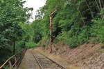 Das ehemalige Vorsignal des Ziegenrücker Bahnhofs steht heute weiterhin auf Einfahrt. Vom Signal bis zum Eingang des hinter der Rechtskurve folgenden Hemmkoppentunnels liegt bis heute noch das für die Betätigung des Signal erforderliche Drahtseile samt Führungen und Umlenkungen. Streckenabschnitt Liebschütz-Ziegenrück der stillgelegten KBS556 / Foto vom 9.7.2022
