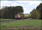DB Cargo DE 18 140 kommt hier am 20.4.2026 um 14.23 Uhr mit einem Containerzug aus Richtung Regensburg bei Laub aus dem Waldeinschnitt.