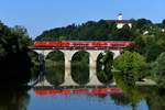 Am Morgen des 14. Juli 2018 floss die Vils ruhig dahin, als sie 146 240 mit ihrem RE 4056 nach Passau bei Vilshofen überquerte. Im Hintergrund ist die Benediktiner-Abtei Schweickelberg zu sehen. 