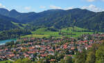 Ein Blick vom Weg auf die Schliersbergalm auf das Zentrum von Schliersee am 22.09.2026: Man muss schon etwas genauer hinsehen, um den aus Bayrischzell kommenden LINT 54 zu entdecken, der gleich den Bahnhof (das gro�e weisse Geb�ude in der linken Bildh�lfte) erreichen wird
