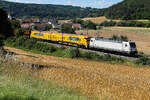 188 101 Northrail mit einer Vossloh Maschine und einpaar Wagen versteckt hinter Büschen am 4 Juli 2026 bei Breitenfurt.