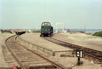 DSB Güterbahnhof Glyngøre: Am 6. September 1976 steht die Rangierdiesellok Mt 159 auf der Bahnanlage in Glyngøre. Die Mt-Rangierlokomotiven baute die Lokomotivfabrik Frichs A/S in Århus; Baujahre: 1957-1960. Die Loks hatten ursprünglich einen Frichs-Dieselmotor des Typs Frichs 8.200CV (425 PS); ab 1970-1971 erhielten sie stattdessen einen Maybach-Mercedes-Dieselmotor (820B, 491 PS). - Bis den 29. Mai 1971 fuhren auf der 28,6 km langen Bahnstrecke Skive - Glyngøre (- Nykøbing Mors) Personenzüge. Mit dem Fährschiff zwischen Glyngøre - im Hintergrund ist das kleine Fährbett zu sehen - und der Stadt Nykøbing Mors auf der anderen Seite des Salling Sund wurden auch Personenwagen überführt. Der Bahngüterverkehr nach Nykøbing Mors wurde bis zum 1. Oktober 1977 aufrechterhalten; nach Glyngøre gab es noch bis den 18. Dezember 1979 Güterzüge. - Die Kleinstadt Glyngøre liegt auf der Halbinsel Salling, während die Stadt Nykøbing Mors sich - wie der Name erklärt - auf der Insel Mors befindet. In Dänemark gibt es drei Städte mit der Bezeichnung  Nykøbing , und um sie zu unterscheiden, fügt man die geografische  Zugehörigkeit  hinzu, also Nykøbing M(ors), Nykøbing F(alster) und Nykøbing Sj(ælland). - Scan eines Farbnegativs. Film: Kodak Kodacolor II. Kamera: Minolta SRT-101.