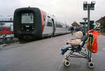 Zwei unterschiedliche Verkehrsmittel im Bahnhof Hillerød am 9. Oktober 2000: Eben angekommen ist die IC2-Garnitur MF 1042 + FS 1142 der Gribskovbanen (GDS). - Auf dem Bahnsteig steht ein  Kindersportwagen , aus dem ein kleiner Junge (: mein damals zweijähriger Sohn Stefan) den Zug und das Treiben im Bahnhof sehr interessiert beobachtet. - Scan eines Farbnegativs. Film: AGFA HDC 200-plus. Kamera: Minolta XG-1.