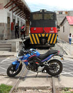 Solange das Motorrad der Begleitcrew (die jeweils die Strassenübergänge bei der Zugsdurchfahrt bewacht) vor der Lok steht, fährt der Zug nicht ab: Halt an einem Unterwegsbahnhof. San Antonio de Ibarra - Ibarra, 07.08.2018