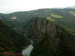 Blick hinunter ins Tal aus der SGLM, deren Trasse in die fast senkrechten Hnge der Schlucht des Flusses Drac gesprengt wurde. Hinten unten im Tal ein Blick auf die Bahn unten im Tal.
29.08. 2007

Die SGLM ist eine meterspurige Gebirgsbahn in den franzsischen Alpen in der Nhe von Grenoble.
Ihre Geschichte unterscheidet sich aber von anderen Gebirgsbahnen. In der Gegend um La Mure gibt es im Gebirge hochwertige Steinkohle. Die SGLM wurde von 1882-1886 als Kohlenbahn zum Abtransport dieser Steinkohle gebaut. Sie fhrt von der Normalspurstation Saint-Georges-de-Commiers (SG) ber 30 Kilometer hoch nach La Mure (LM).
Sie wurde 1903 mit 2400 Volt Gleichspannung elektrifiziert. Ursprnglich geschah dies mit einer doppelten Oberleitung mit +1200V und -1200V und den Schienen als Mittelleiter.
Ab 1906 wurde eine Verlngerung der Bahn von La Mure bis zur Departementshauptstadt Gap (Strecke LM-G) in den Alpen projektiert. So entstand auch der Name, SGLM-G (St Georges-La Mure - Gap), welcher an manchen Fahrzeugen bis heute zu finden ist.
Das Gesamtprojekt wurde nie komplett verwirklicht und nachdem die Verlngerung den Ort Corps erreichte hatte, stellte man die weit fortgeschrittenen Arbeiten 1932 ein.
Wie die kurzlebige Verlngerung erhielt dann auch die Stammstrecke eine normale Fahrleitung fr 2400V.
Die Stammstrecke blieb fr den Kohlentransport bis zuletzt bedeutend. Die letzte Kohlegrube wurde erst 1997 geschlossen und nach Ende der Kohlentransporte 1988 wird die Strecke als Touristenbahn weiter betrieben.
