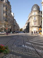 In der Altstadt von Reims an der Kreuzung Place de l´Hôtel de Ville und Rue Thiers finden sich noch Spuren des alten bereits 1939 stillgelegten meterspurigen Straßenbahnnetzes.
Hinter den alten Tramschienen sieht man am Ende der Rue Thiers zwei Fahrzeuge der 2011 eröffneten neuen Straßenbahn. Die neue Tram nimmt hier dann einen anderen Weg durch breitere Straßen.
2014-10-19 Reims