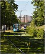 . Im Grnen - Zwischen den Station  Campus Croix Rouge  und  Saint John Perse  verluft die Bahnstrecke durch ein kleines Waldstck. Hier begegnen sich zwei Bahnen mit einem architektonisch markanten Hrsaalgebude im Hintergrund. 23.07.2012 (Jonas)