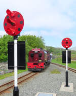 In Rhyd Ddu mit den speziellen Signalen fährt der Gegenzug von Caernarfon nach Porthmadog ein. Das Herauslehnen des Lokpersonals ist eine häufig gesehene Position, weil der Blick aus dem Führerstand doch stark eingeschränkt ist. Rhyd Ddu, 14.5.2022